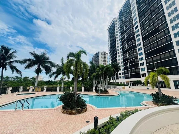 a view of a swimming pool with a lawn chairs and palm trees