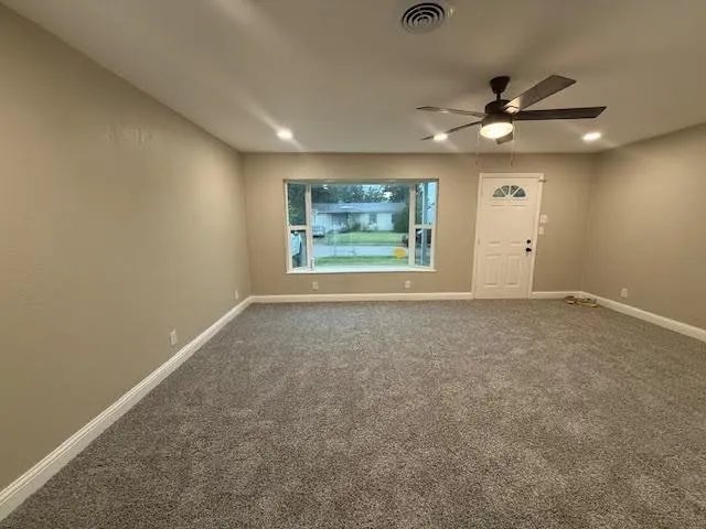 an empty room with windows and fan