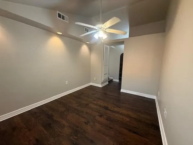en empty room with wooden floor and fan