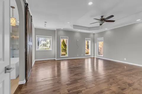 a view of an empty room with wooden floor and windows