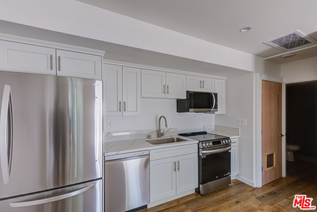 11906 Rochester Avenue Los Angeles, CA 90025 - Photo 5 of 13 a kitchen with stainless steel appliances a refrigerator stove and sink