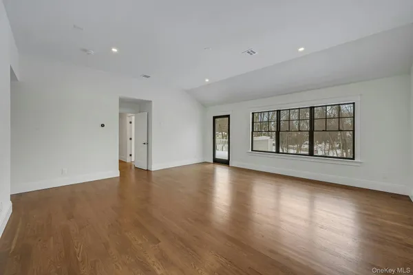 a view of an empty room with a window and wooden floor