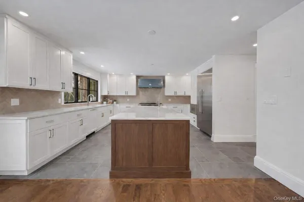 a kitchen with stainless steel appliances granite countertop a refrigerator sink and white cabinets