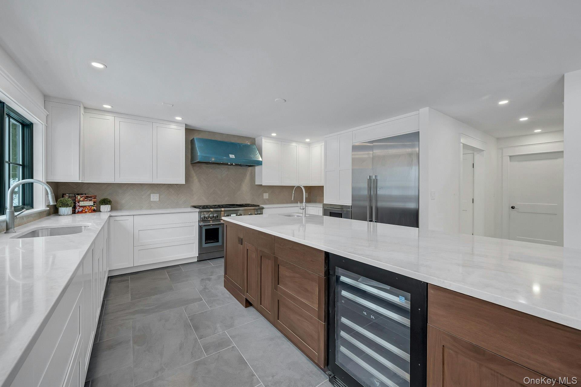 32 Sycamore Road Scarsdale, NY 10583 - Photo 9 of 48 Kitchen featuring quartz counters, white cabinets, a wine cooler, an expansive kitchen island, and Thermador stainless steel appliances