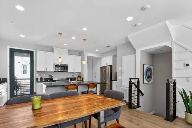 a kitchen with stainless steel appliances granite countertop a sink a stove a refrigerator cabinets a dining table and chairs