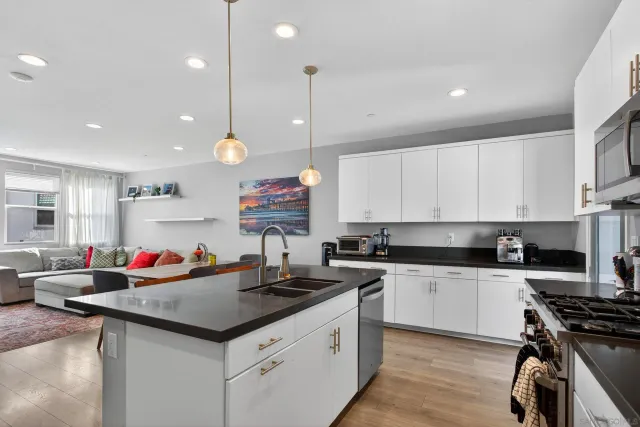 a kitchen with kitchen island granite countertop a sink and a refrigerator