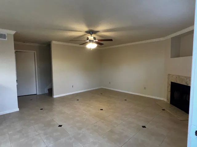 an empty room with a chandelier fan and windows