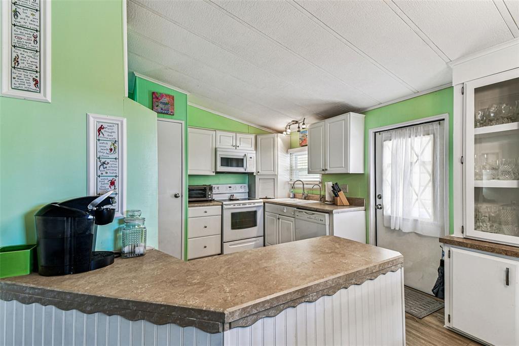 12501 Ulmerton Road, Unit 71 Largo, FL 33774 - Photo 11 of 75 a kitchen with a refrigerator a stove top oven a sink dishwasher and wooden cabinets with wooden floor