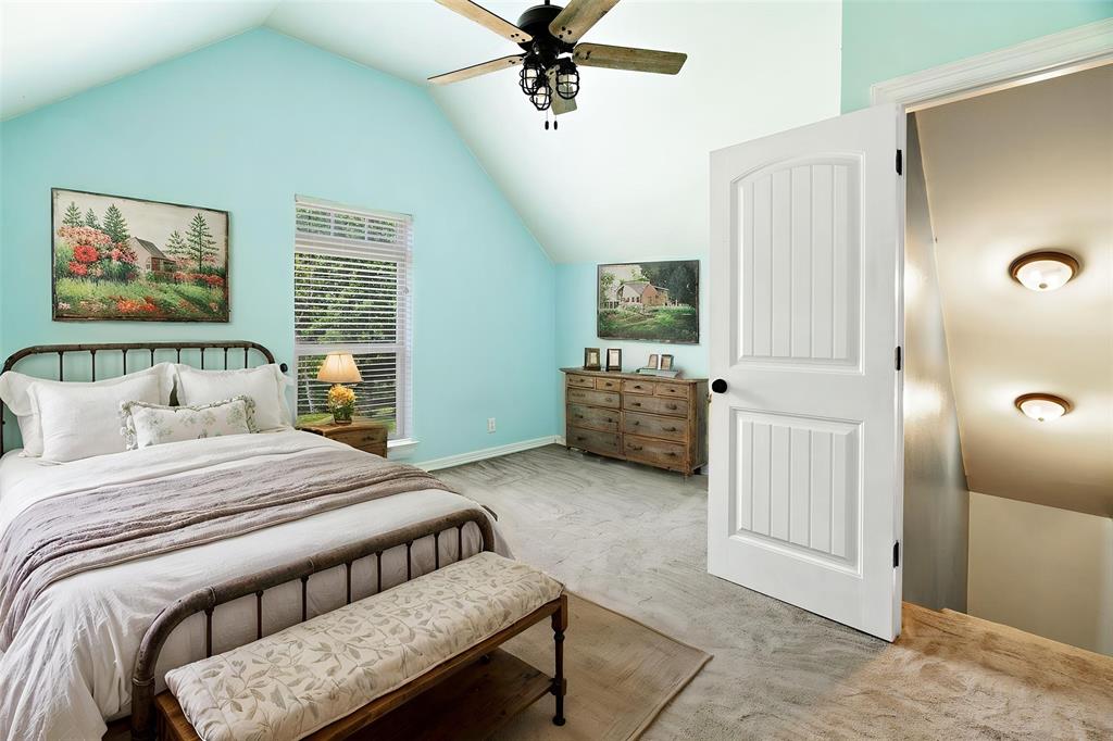 821 County Road Paris, TX 75462 - Photo 21 of 40 Vaulted ceiling featuring a ceiling fan with wood-finish blades, wood-finish flooring, a window with blinds, and a white panel door