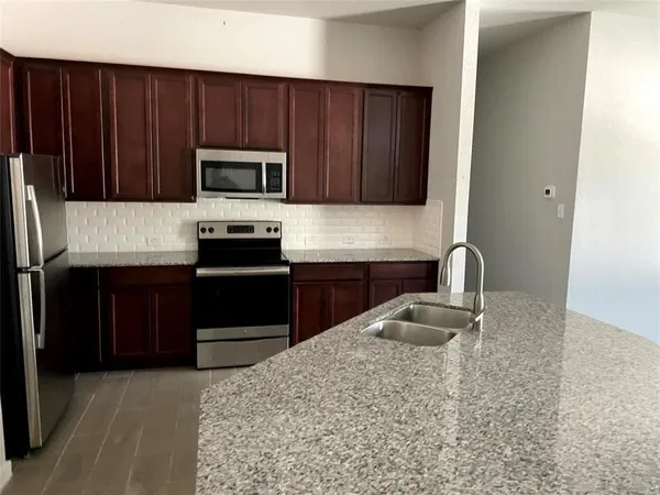 a kitchen with granite countertop a refrigerator stove top oven and sink