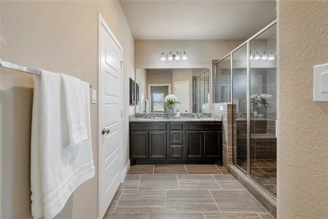 a bathroom with a mirror a double vanity sink and glass door