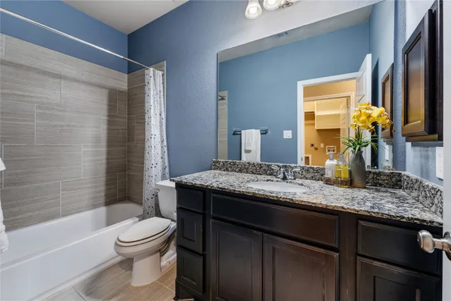 a bathroom with a granite countertop sink toilet and shower