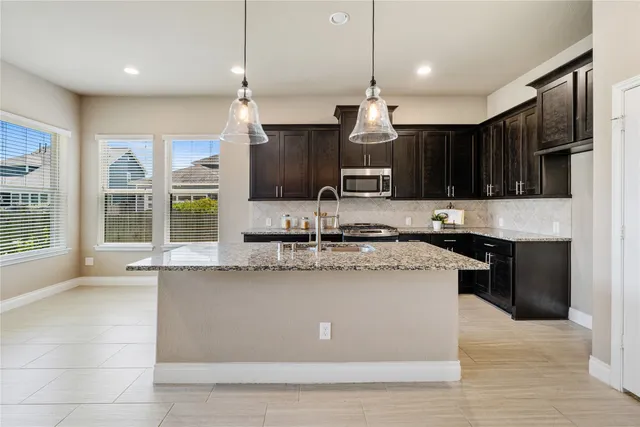 a kitchen with stainless steel appliances granite countertop a sink a stove a refrigerator and a oven