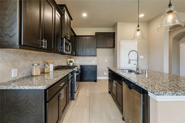 a kitchen with granite countertop stainless steel appliances a sink stove and cabinets