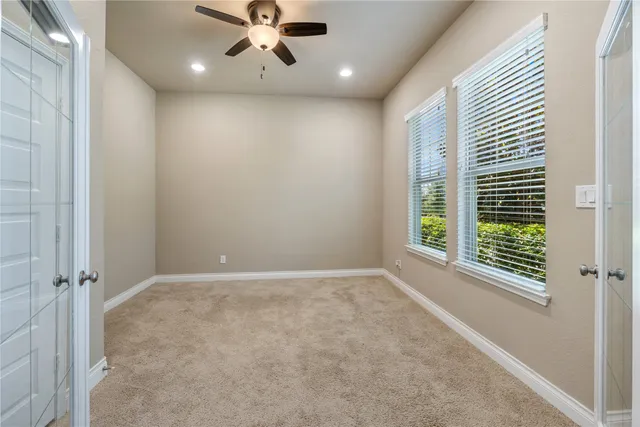 an empty room with windows and fan
