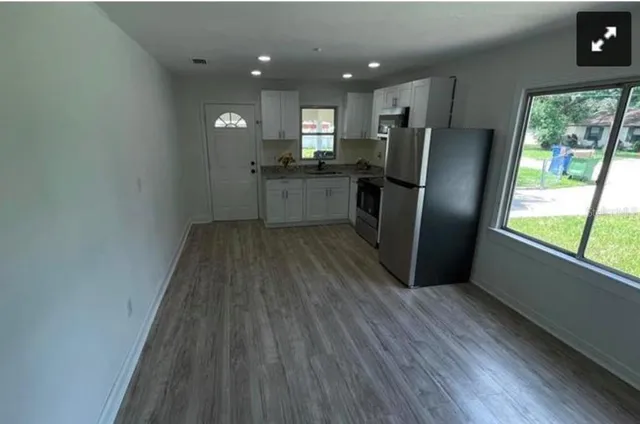 a kitchen with stainless steel appliances granite countertop a refrigerator a sink a stove a microwave and island with wooden floor