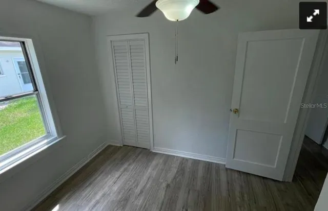 a view of an empty room with wooden floor and a window