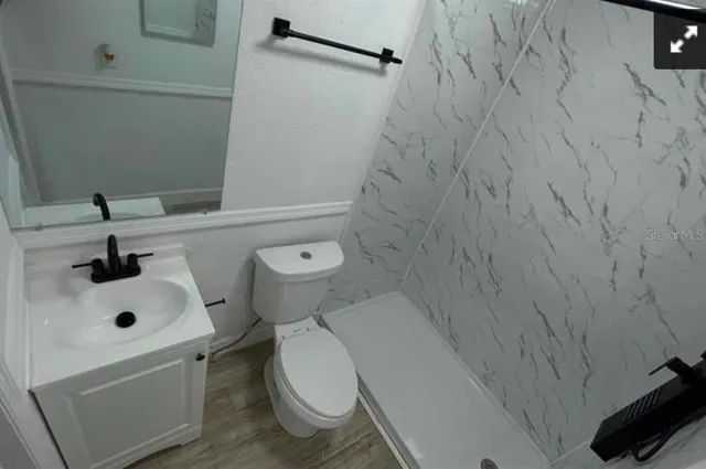 a white toilet sitting next to a white sink and vanity