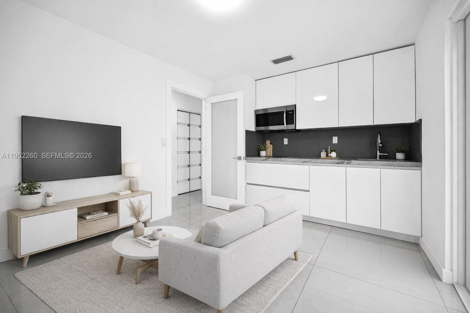 13284 Southwest 39th Street Miami, FL 33175 - Photo 37 of 67 a living room with furniture a flat screen tv and white kitchen