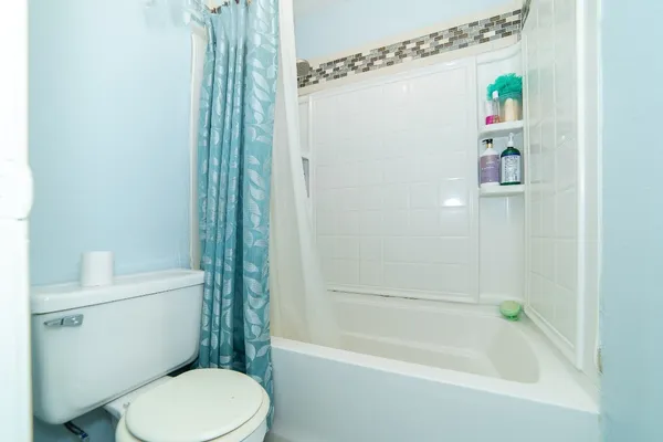 a white toilet sitting next to a bath tub