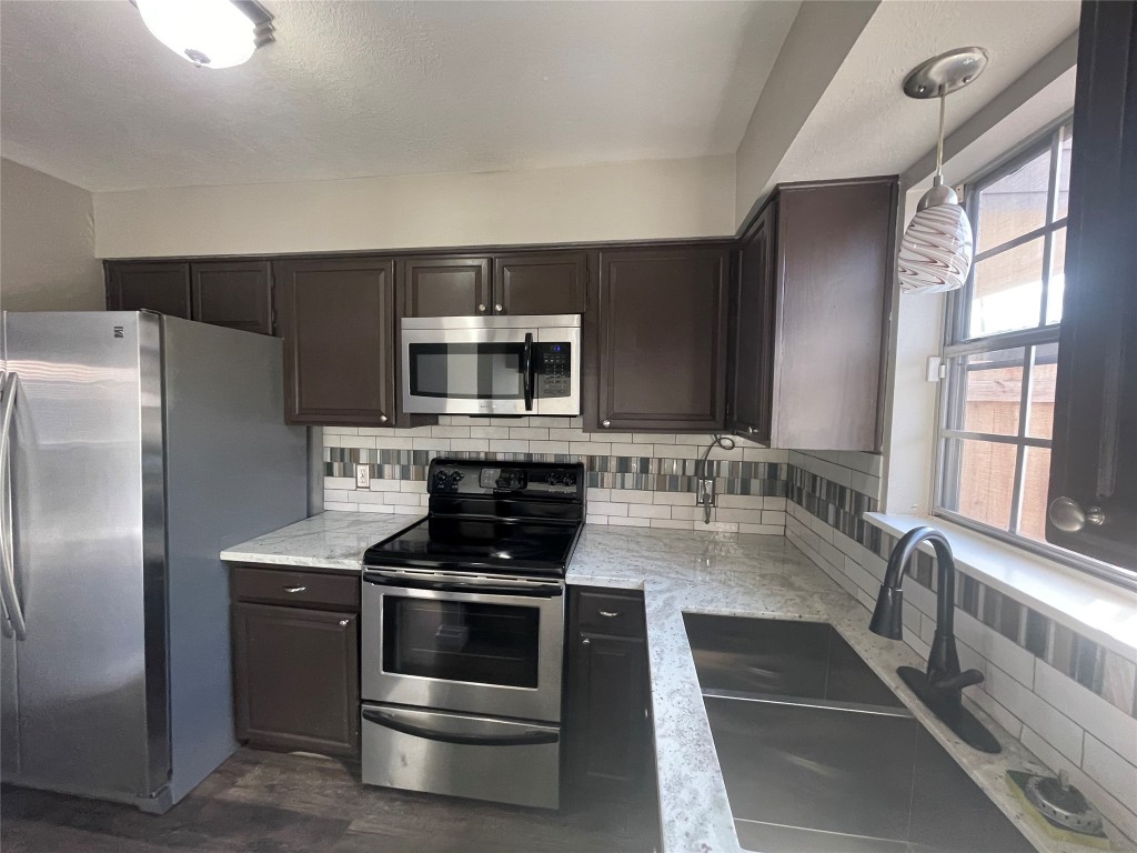 4866 Milwee Street, Unit 22 Houston, TX 77092 - Photo 5 of 23 a kitchen with stainless steel appliances a stove a sink and a microwave