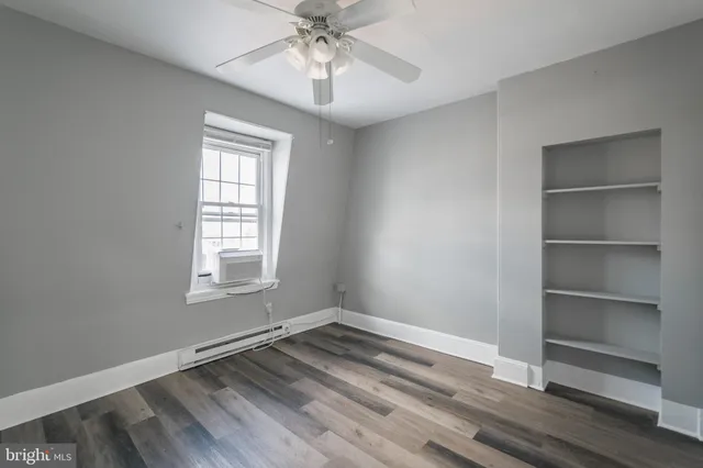 a view of an empty room with a window and wooden floor