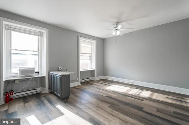 a view of an empty room with window and wooden floor
