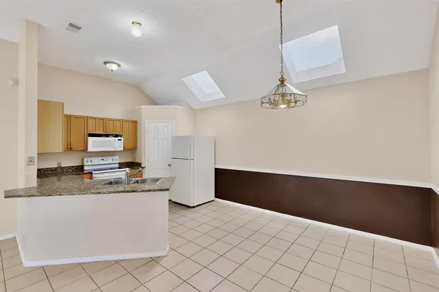an empty room with chandelier fan and windows