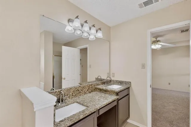 an empty room with chandelier fan and windows