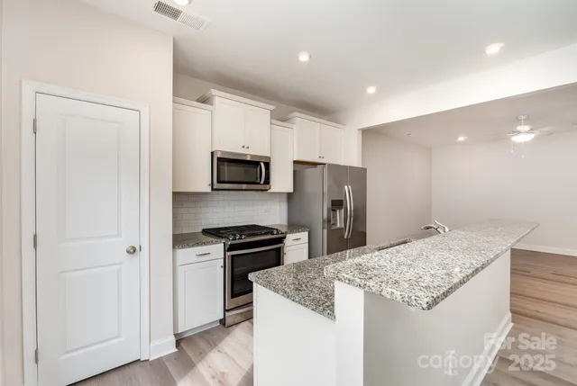 a kitchen with stainless steel appliances kitchen island granite countertop a refrigerator and a sink