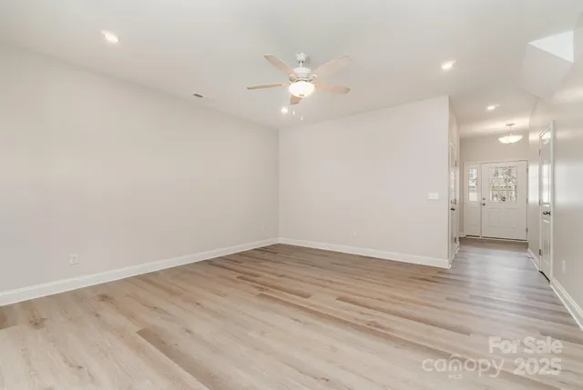 an empty room with wooden floor and a ceiling fan
