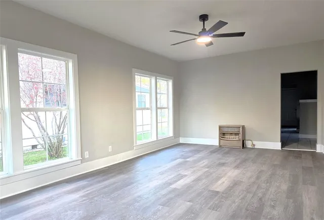 an empty room with windows and ceiling fan