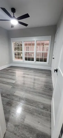 a view of an empty room with a window and wooden floor