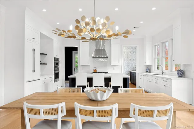 a kitchen with stainless steel appliances kitchen island granite countertop a dining table chairs and white cabinets
