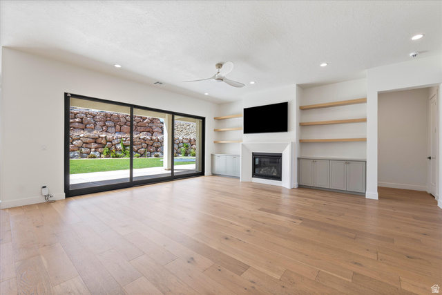 1192 East Corral Way Washington, UT 84780 - Photo 24 of 81 Spacious living area featuring light wood-finish flooring, a contemporary fireplace with a mounted television, and recessed lighting