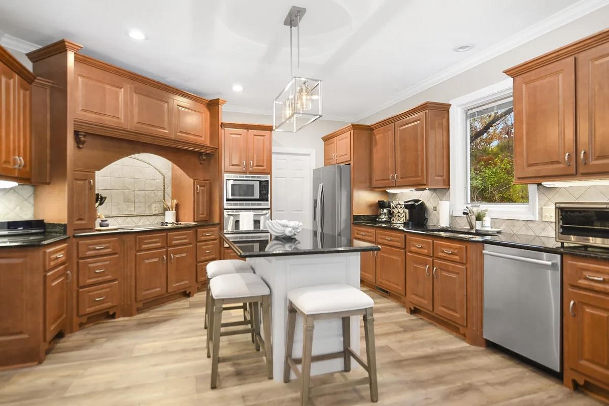 505 Sailboat Point Savannah, TN 38372 - Photo 7 of 40 a kitchen with stainless steel appliances granite countertop wooden cabinets a stove a sink a dining table and chairs