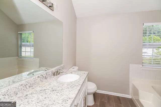 a bathroom with a granite countertop sink a toilet and a window