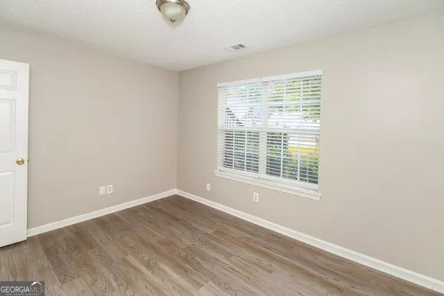 a view of an empty room with wooden floor and a window