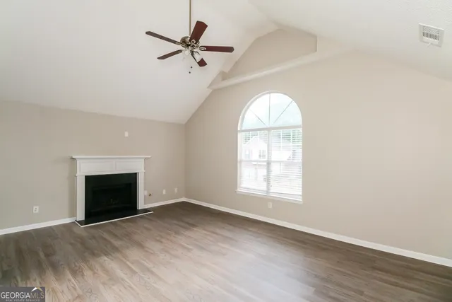 an empty room with wooden floor fireplace and windows
