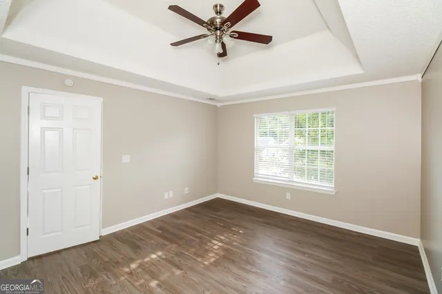 an empty room with wooden floor fan and windows