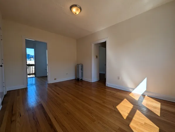 a view of an empty room with wooden floor and a window
