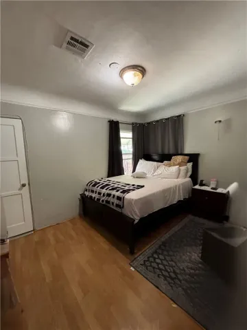 a spacious bedroom with a bed and a dresser with wooden floor