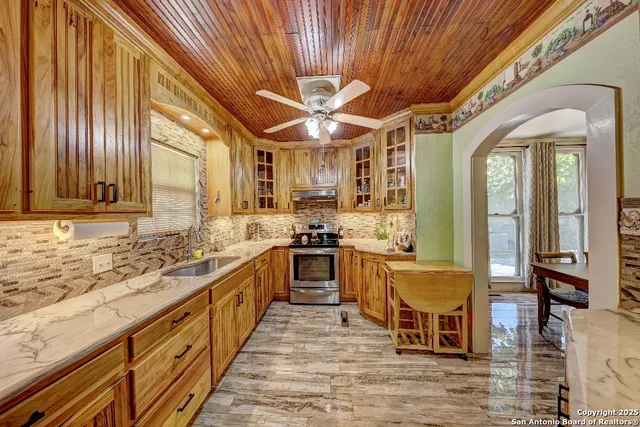 a large kitchen with stainless steel appliances granite countertop a stove a sink dishwasher and a dining table with wooden floor