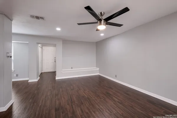 an empty room with wooden floor and windows