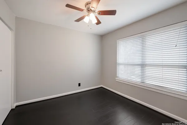 an empty room with a window and a fan