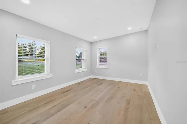 an empty room with wooden floor and windows