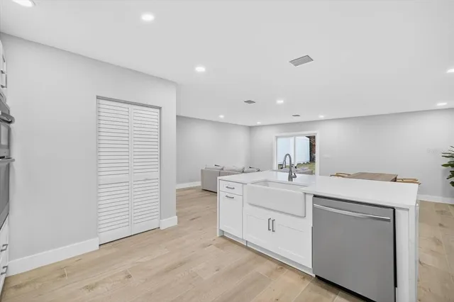 a view of a kitchen with a sink and dishwasher with white cabinets