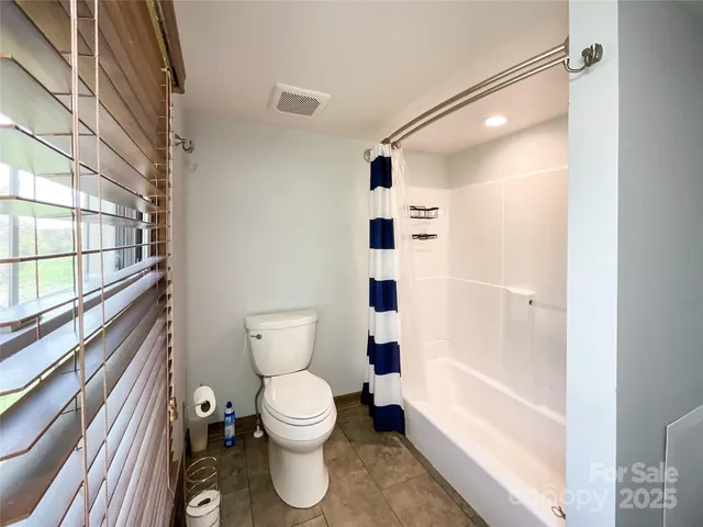 an empty room with wooden floor and windows with curtains
