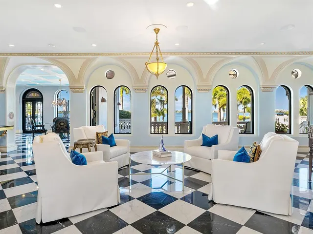 a living room with a black white checkered floor with a gaming machine and dining chairs