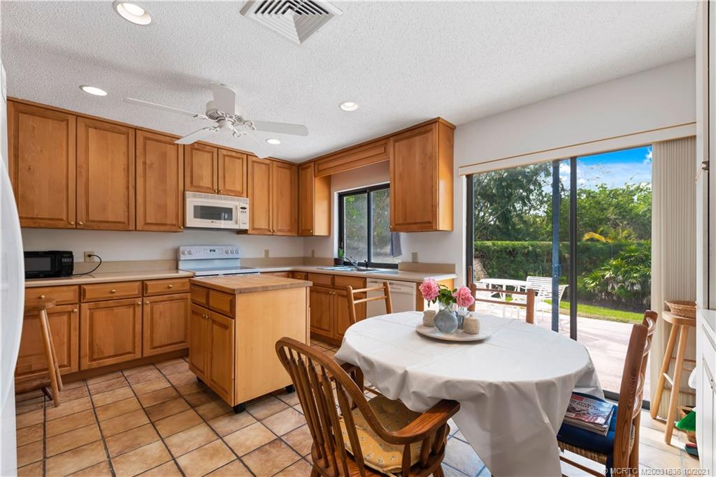 114 North Beach Road Hobe Sound, FL 33455 - Photo 20 of 37 a kitchen with stainless steel appliances granite countertop a stove a sink dishwasher a dining table and chairs with wooden floor